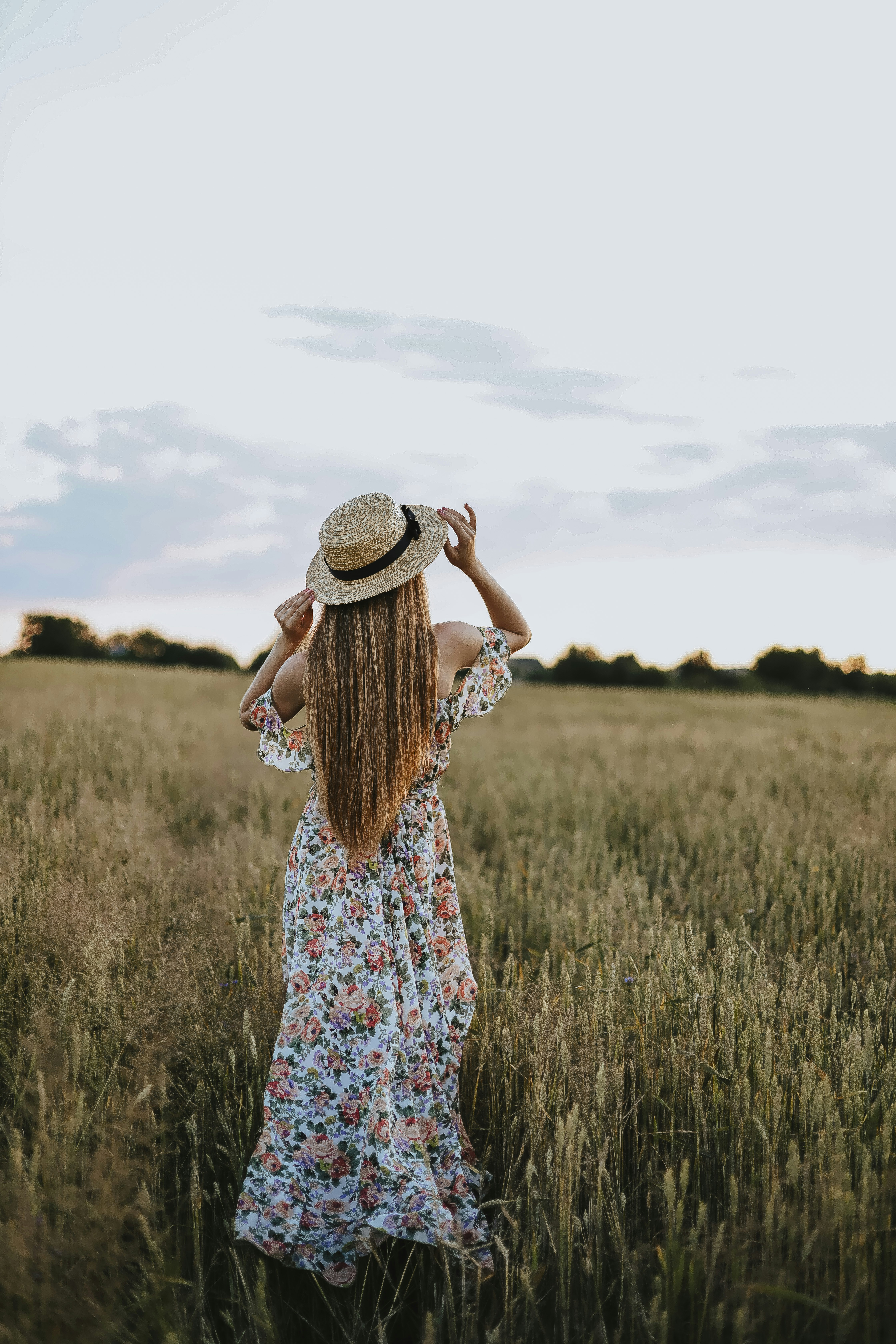 Feminine girl wearing floral dress and hat standing calmly on farm – gentle image of faith-based encouragement for worried hearts seeking peace through scripture and prayer